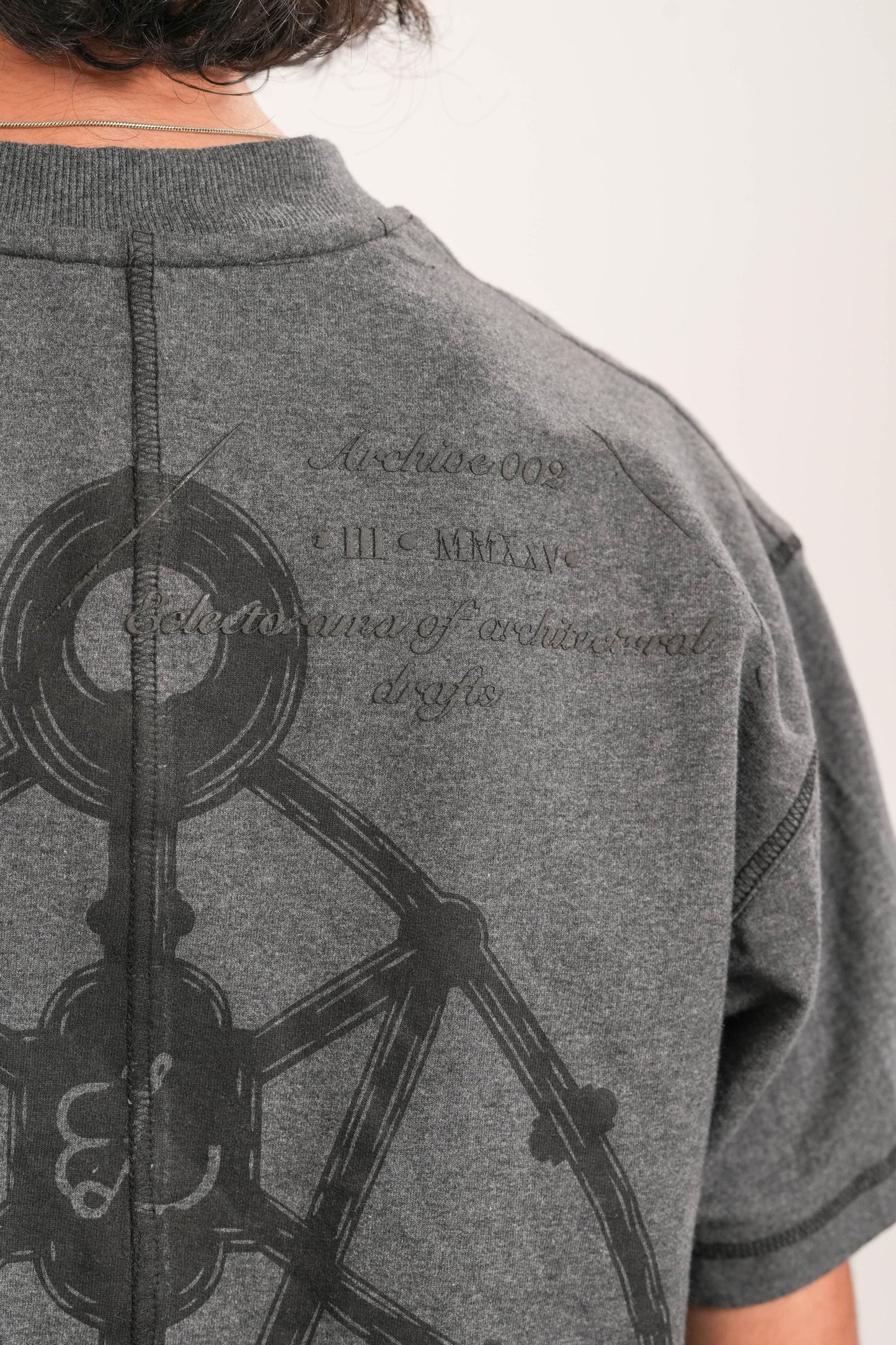 Close-up of grey t-shirt back with black geometric print and stitched seam detail