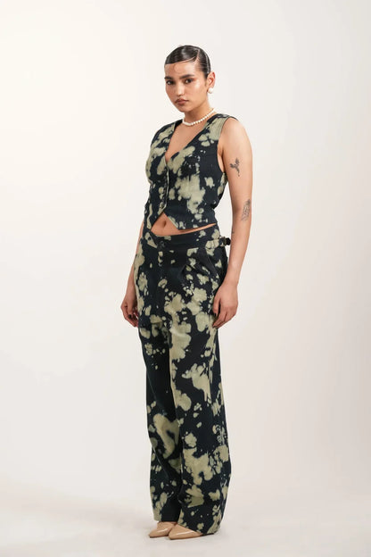 Fashion model wearing black and beige tie-dye vest and wide-leg pants with pearl necklace and nude heels
