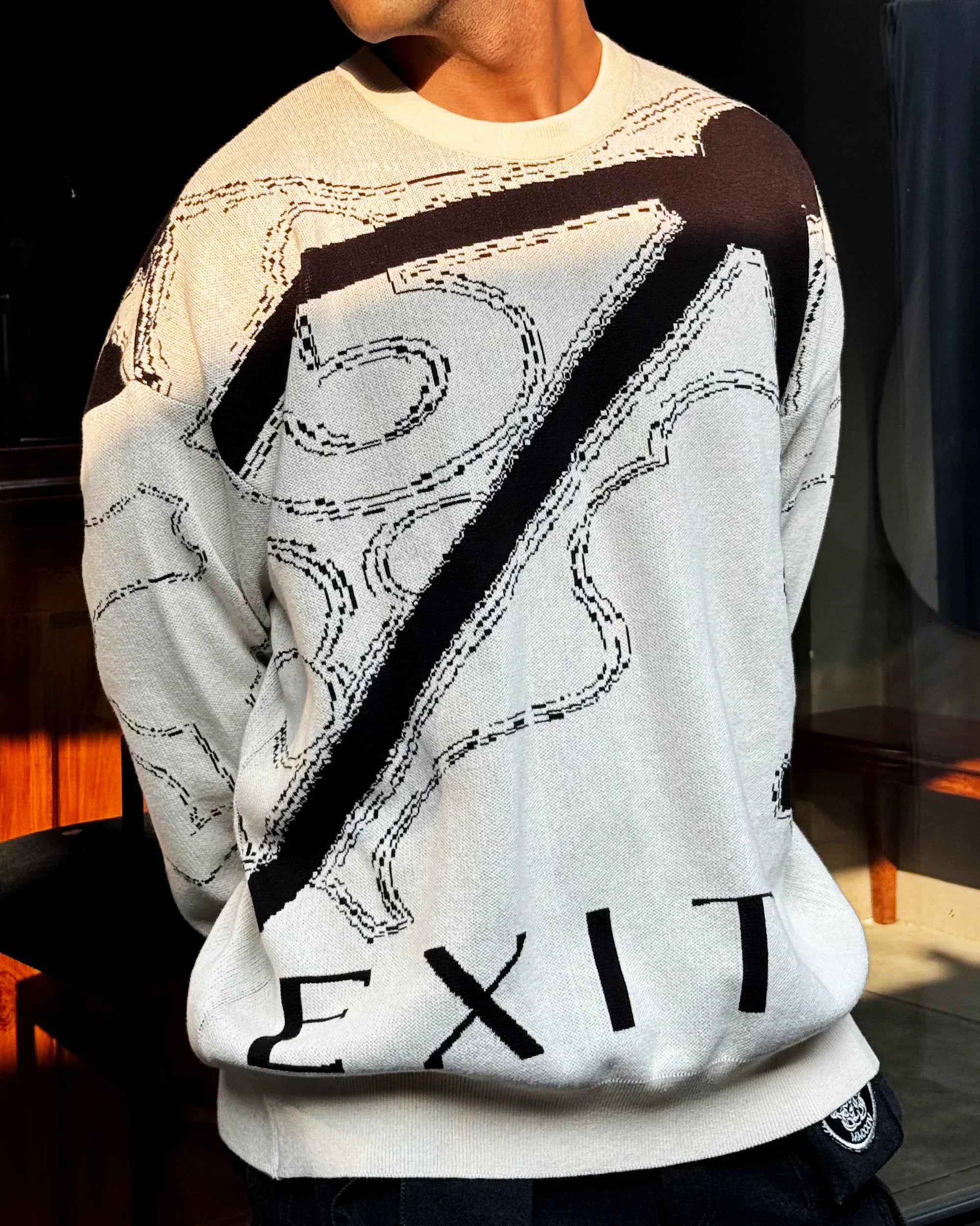 Close-up of person wearing beige sweater with large black number 57 and word EXIT in bold knit design