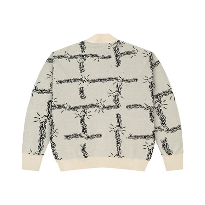 Cream knit sweater with black broken chain pattern and ribbed cuffs and hem