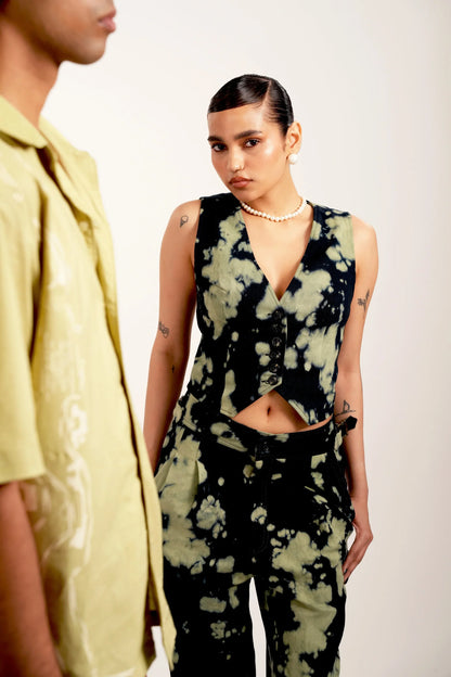 Fashion model in black and green tie-dye vest and pants with pearl necklace and earrings